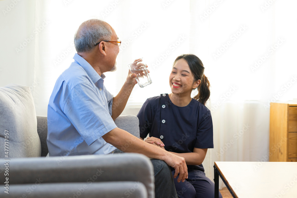 Smiling nurse giving glass of water to senior asian man in nursing home or assisted living facility. Smiling nurse giving glass of water to senior asian man in nursing home or assisted living facility.