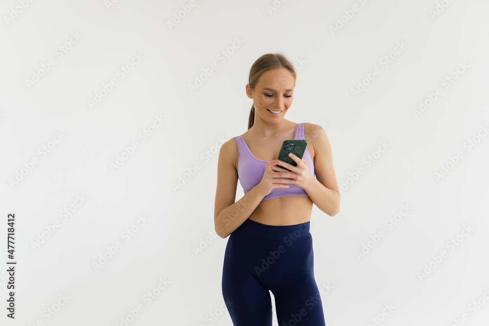 Smiling fitness woman using phone isolated on a white background Smiling fitness woman using phone isolated on a white background
