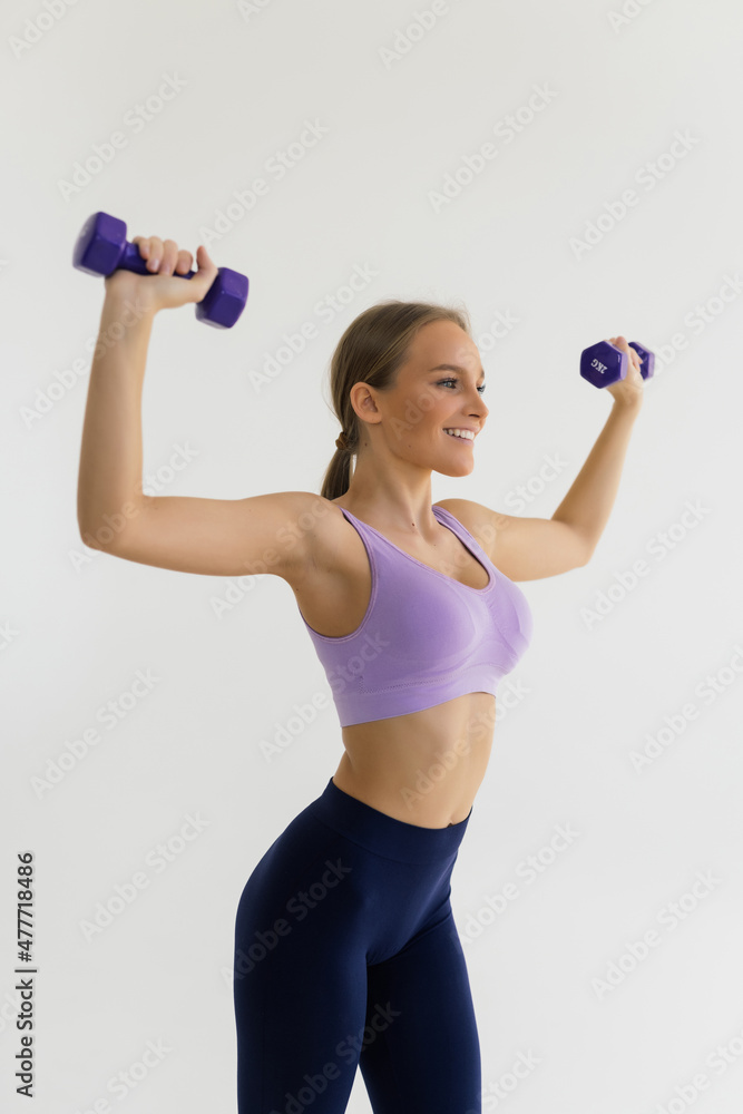 Athletic young woman works out with dumbbells isolated on white background Athletic young woman works out with dumbbells isolated on white background