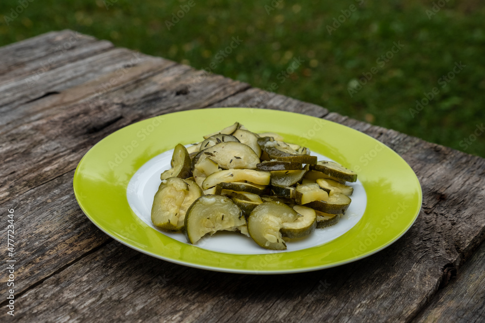 Zucchini Salat auf einem grünen Teller auf einem hölzernen rustikalen Tisch im Garten