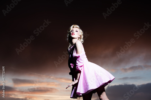 Woman in monroe dress on dramatic sky. Female model in a fashion dress outdoor. © Volodymyr