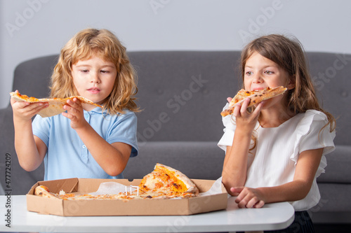Children eating pizza. Little children friends  boy and girl bite pizza.