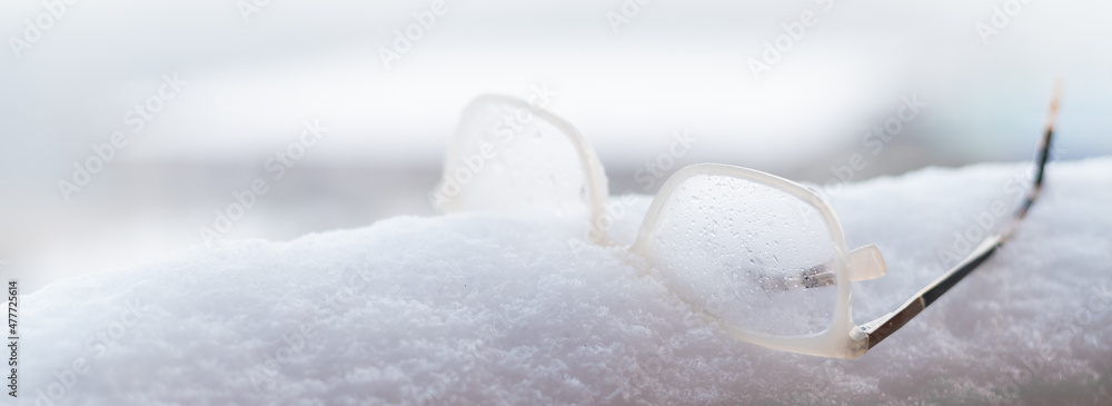 Women's glasses with white frames on the snow. Widescreen.