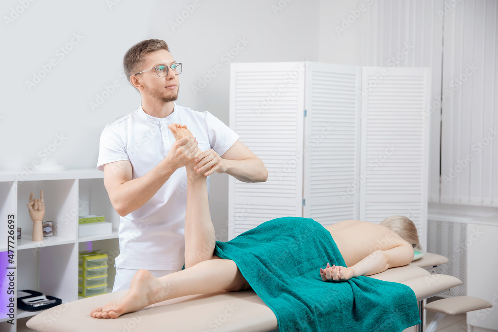 Fototapeta premium Concept sports massage for woman. Osteopath therapist working with legs muscle athlete after workout