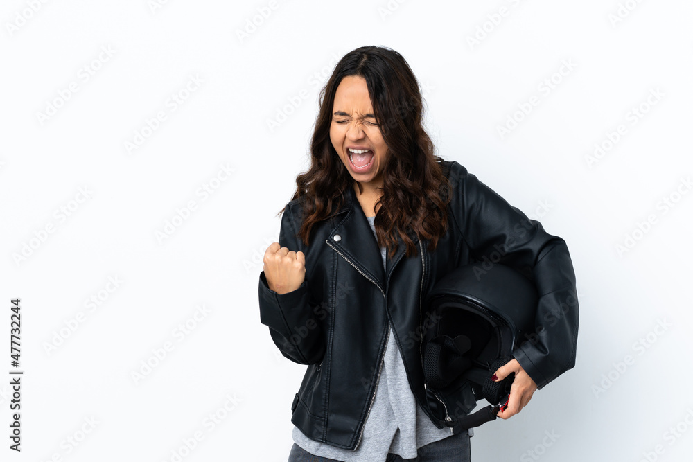 Young woman holding a motorcycle helmet over isolated white background celebrating a victory Young woman holding a motorcycle helmet over isolated white background celebrating a victory