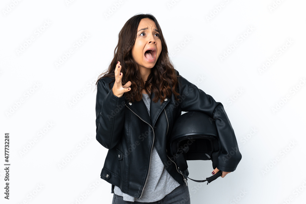 Young woman holding a motorcycle helmet over isolated white background with surprise facial expression Young woman holding a motorcycle helmet over isolated white background with surprise facial expression