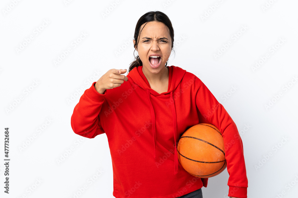 Young woman playing basketball over isolated white background frustrated and pointing to the front
