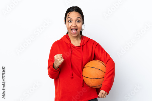 Young woman playing basketball over isolated white background celebrating a victory in winner position © luismolinero