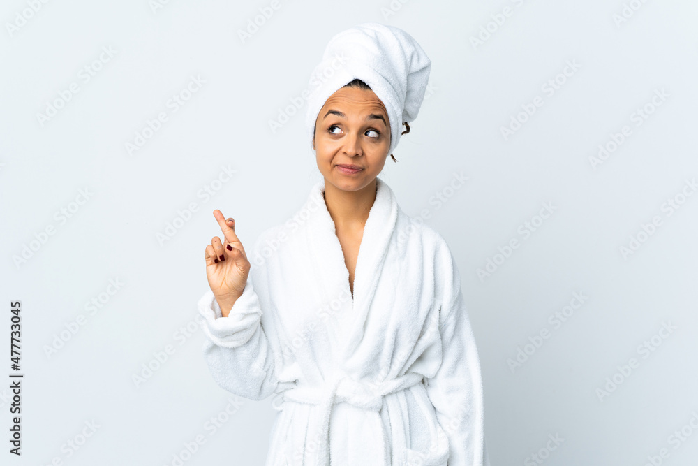Young woman in bathrobe over isolated white background with fingers crossing and wishing the best