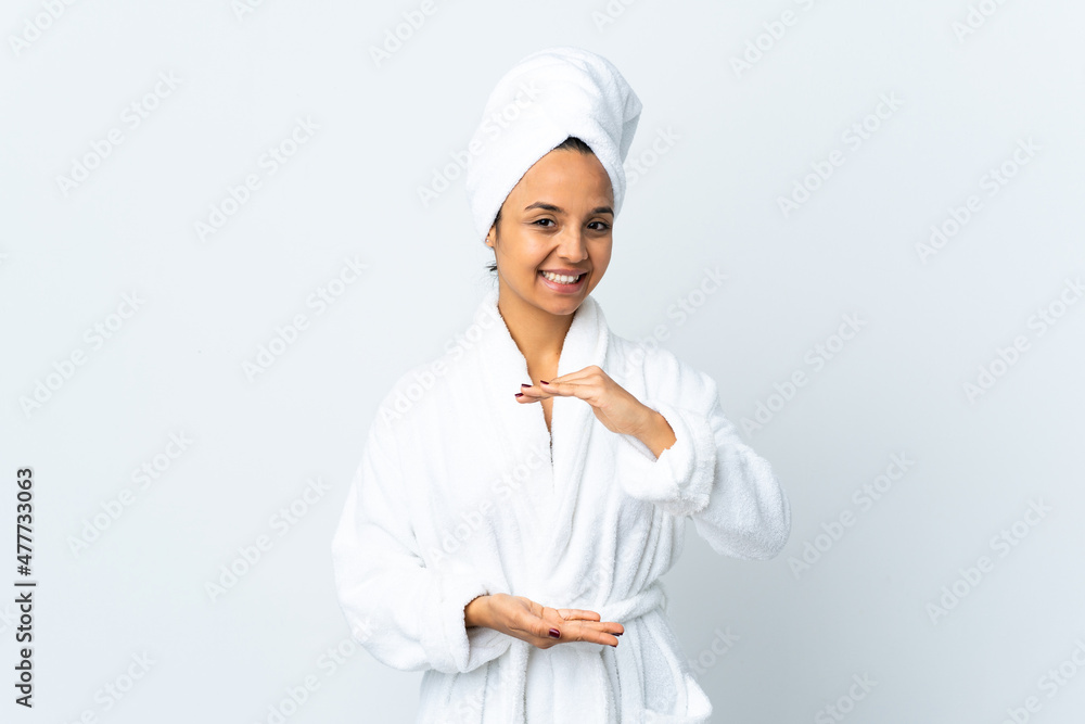 Young woman in bathrobe over isolated white background holding copyspace imaginary on the palm to insert an ad Young woman in bathrobe over isolated white background holding copyspace imaginary on the palm to insert an ad