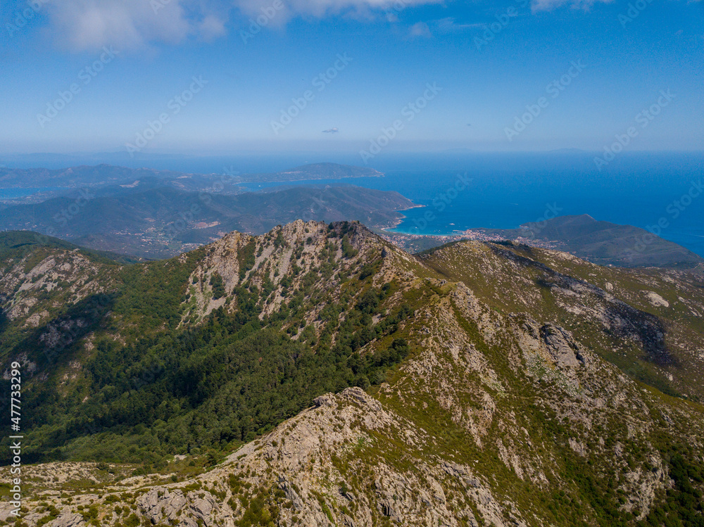 Panorama aerial drone landscape of Monte Capanne, highest moutain on Elba with green landscape and mediterranean sea in the backgroud	
