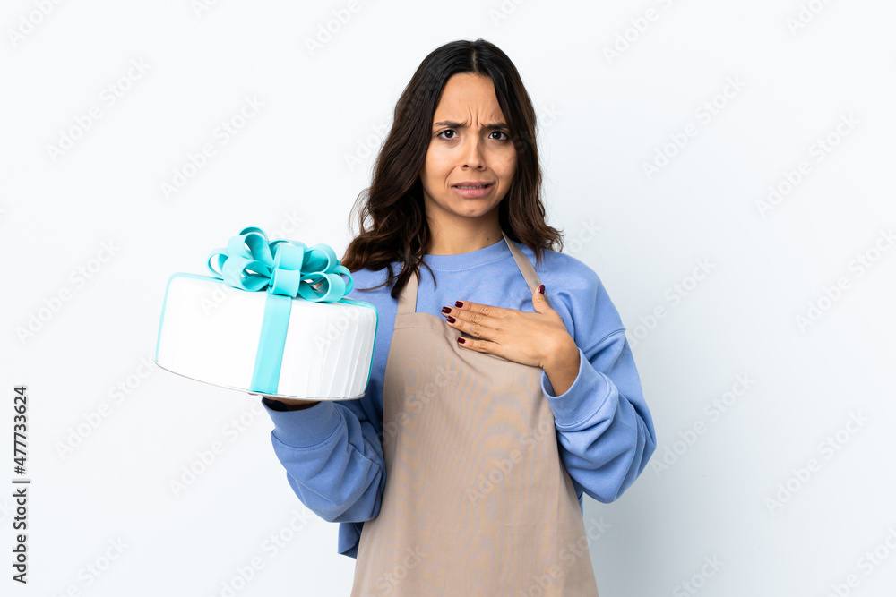 Pastry chef holding a big cake over isolated white background pointing to oneself Pastry chef holding a big cake over isolated white background pointing to oneself