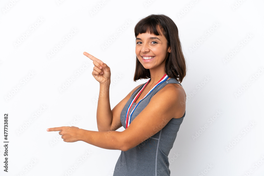 Young mixed race woman with medals isolated on white background pointing finger to the side and presenting a product Young mixed race woman with medals isolated on white background pointing finger to the side and presenting a product