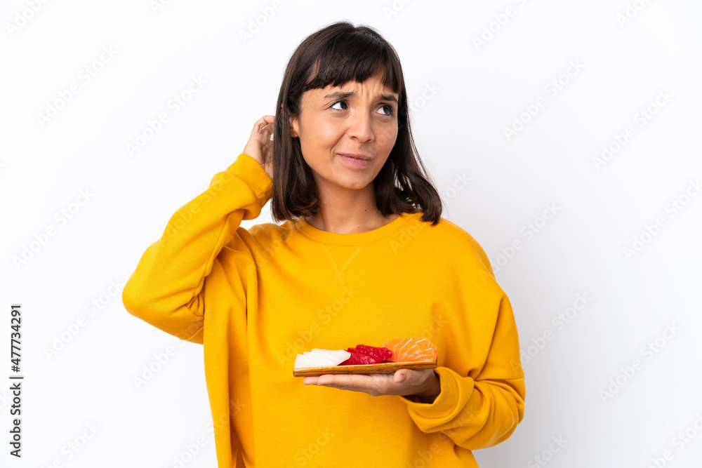 Young mixed race woman holding sashimi isolated on white background having doubts Young mixed race woman holding sashimi isolated on white background having doubts