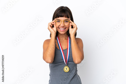 Young mixed race woman with medals isolated on white background with glasses and surprised