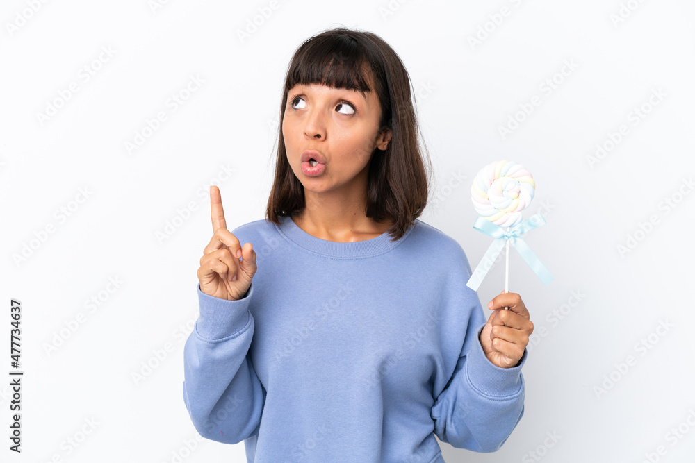 Young mixed race woman holding a lollipop isolated on white background thinking an idea pointing the finger up Young mixed race woman holding a lollipop isolated on white background thinking an idea pointing the finger up