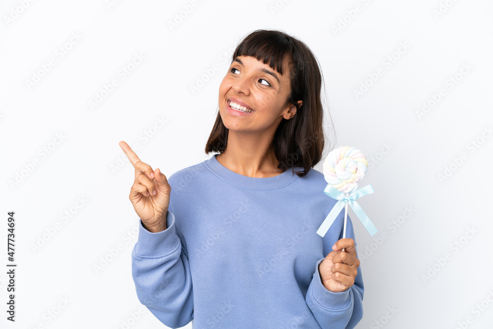 Young mixed race woman holding a lollipop isolated on white background pointing up a great idea Young mixed race woman holding a lollipop isolated on white background pointing up a great idea
