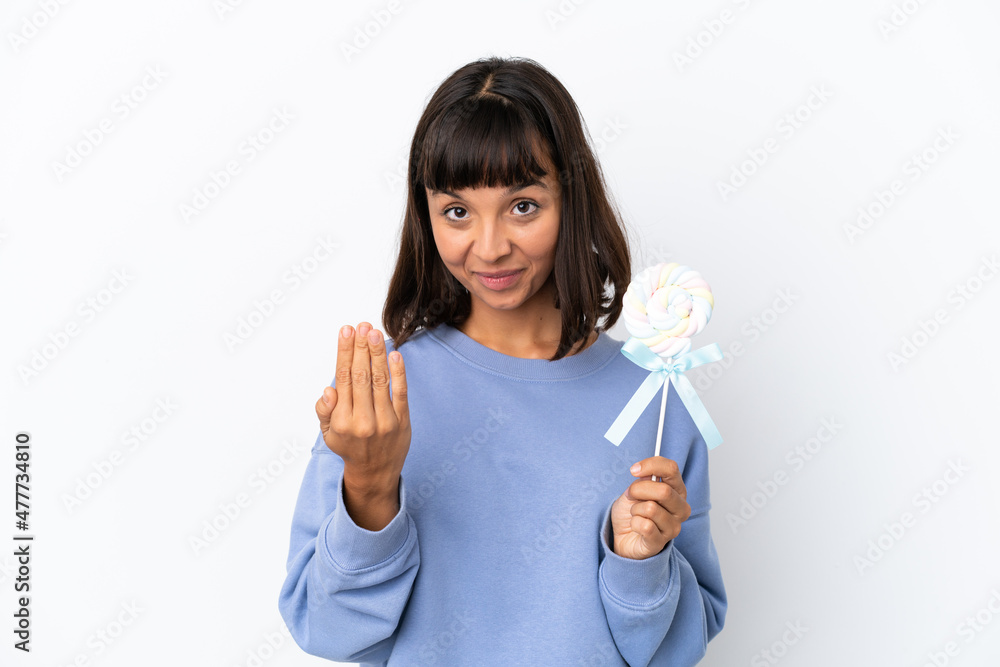 Young mixed race woman holding a lollipop isolated on white background inviting to come with hand. Happy that you came Young mixed race woman holding a lollipop isolated on white background inviting to come with hand. Happy that you came