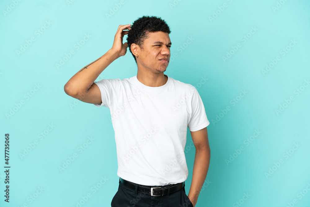 Young African American man isolated on blue background having doubts while scratching head