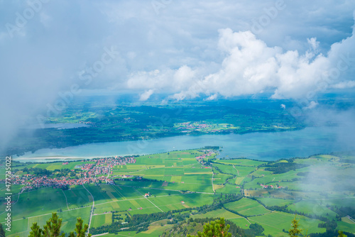 Germany, Tegelberg mountain view in allgaeu bavarian nature landscape foggy atmosphere above forgensee lake and city houses © Simon
