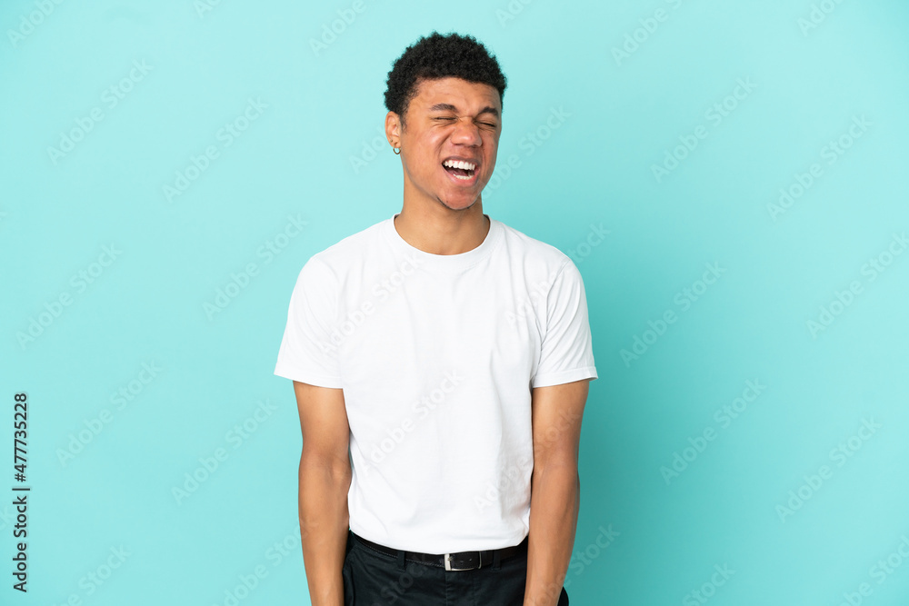 Young African American man isolated on blue background shouting to the front with mouth wide open Young African American man isolated on blue background shouting to the front with mouth wide open