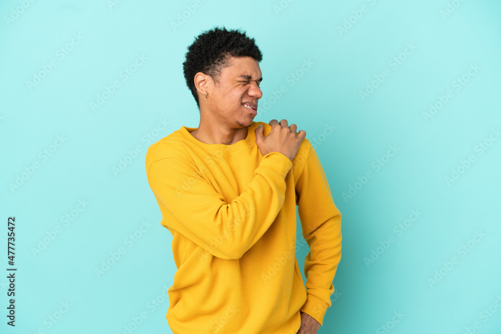 Young African American man isolated on blue background suffering from pain in shoulder for having made an effort Young African American man isolated on blue background suffering from pain in shoulder for having made an effort