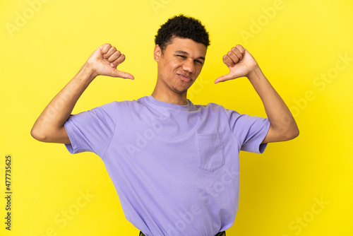 Young African American man isolated on yellow background proud and self-satisfied