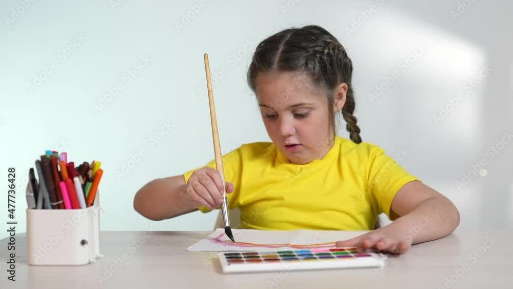 Child girl drawing a rainbow. child artist draws at the table in kindergarten. coronavirus pandemic stay home concept. kid draws a rainbow indoor. school kindergarten drawing lesson Child girl drawing a rainbow. child artist draws at the table in kindergarten. coronavirus pandemic stay home concept. kid draws a rainbow indoor. school kindergarten drawing lesson