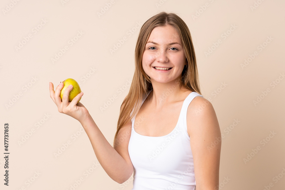 Teenager Ukrainian girl isolated on beige background with an apple Teenager Ukrainian girl isolated on beige background with an apple