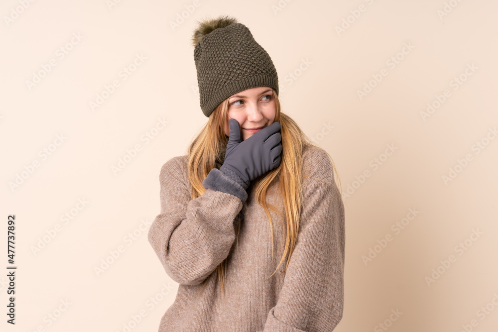 Teenager Ukrainian girl with winter hat isolated on beige background thinking an idea Teenager Ukrainian girl with winter hat isolated on beige background thinking an idea