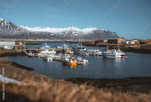 Djupivogur fishing village full of colorful boats in Iceland. Winter scenery with snow capped mountains. © Mathias