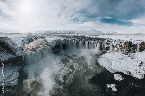 Drone shot of Godafoss waterfall  Iceland  taken from a high angle. Aerial view of the powerful cascade  river and snow covered rocks. Late autumn  early winter scene.