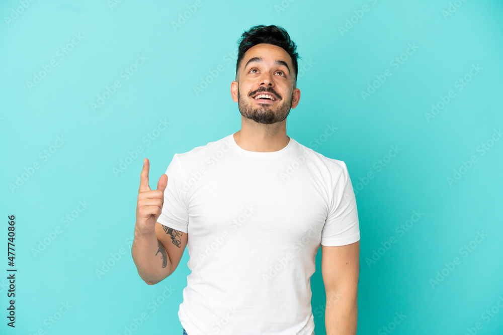 Young caucasian man isolated on blue background pointing up and surprised Young caucasian man isolated on blue background pointing up and surprised