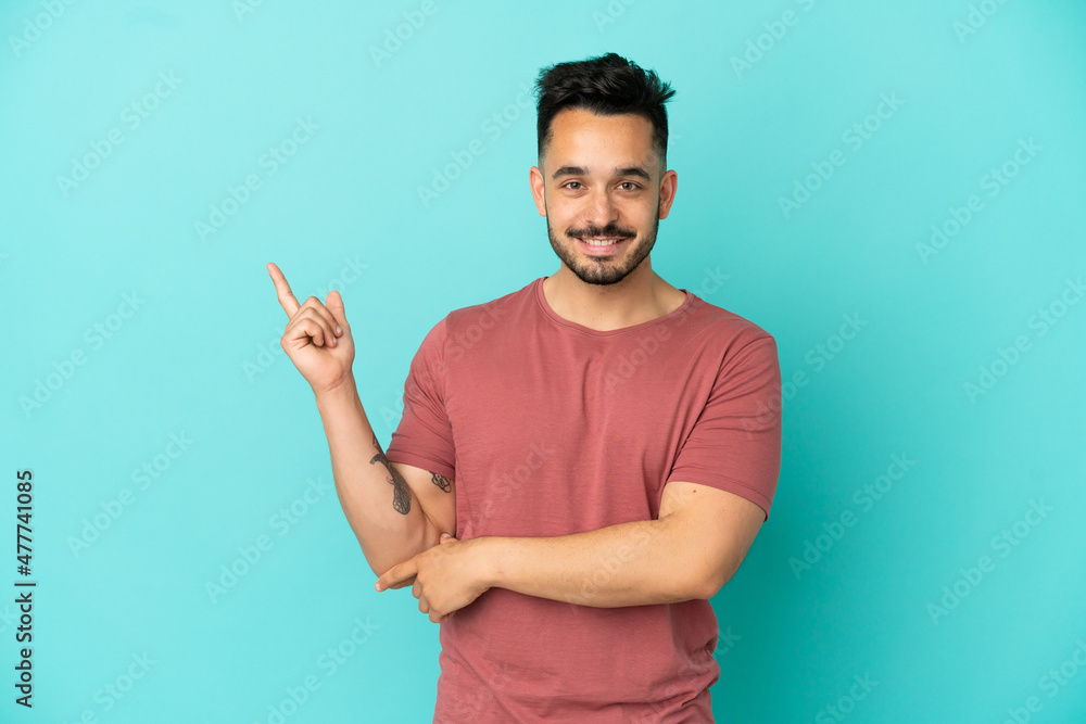 Young caucasian man isolated on blue background happy and pointing up Young caucasian man isolated on blue background happy and pointing up