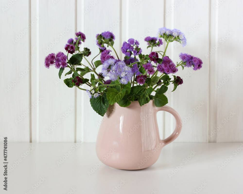 Fototapeta premium pink jug with a purple bouquet of ageratum.