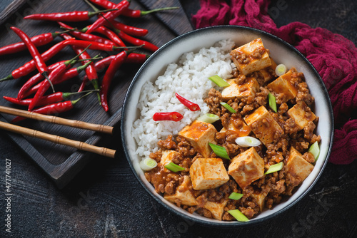Bowl of chinese traditional mapo tofu and white rice, high angle view on a dark brown stone background, studio shot