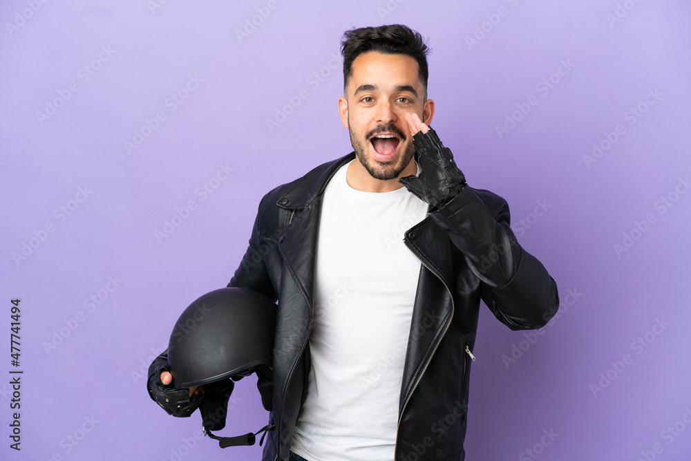 Young man with a motorcycle helmet isolated on purple background shouting with mouth wide open Young man with a motorcycle helmet isolated on purple background shouting with mouth wide open
