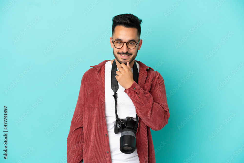 Young photographer caucasian man isolated on blue background with glasses and smiling Young photographer caucasian man isolated on blue background with glasses and smiling