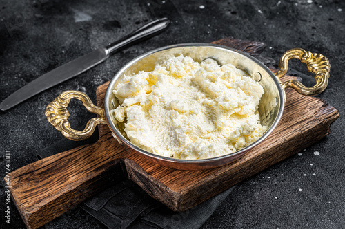 Kaymak Clotted cream, butter cream in a rustic pan. Black background. Top view photo