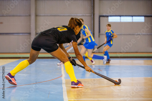 Young woman hockey player playing indoor hockey game
