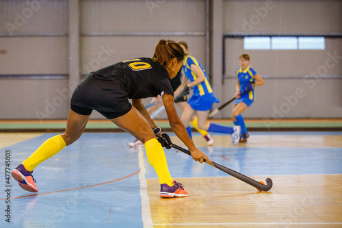 Young woman hockey player playing indoor hockey game photo