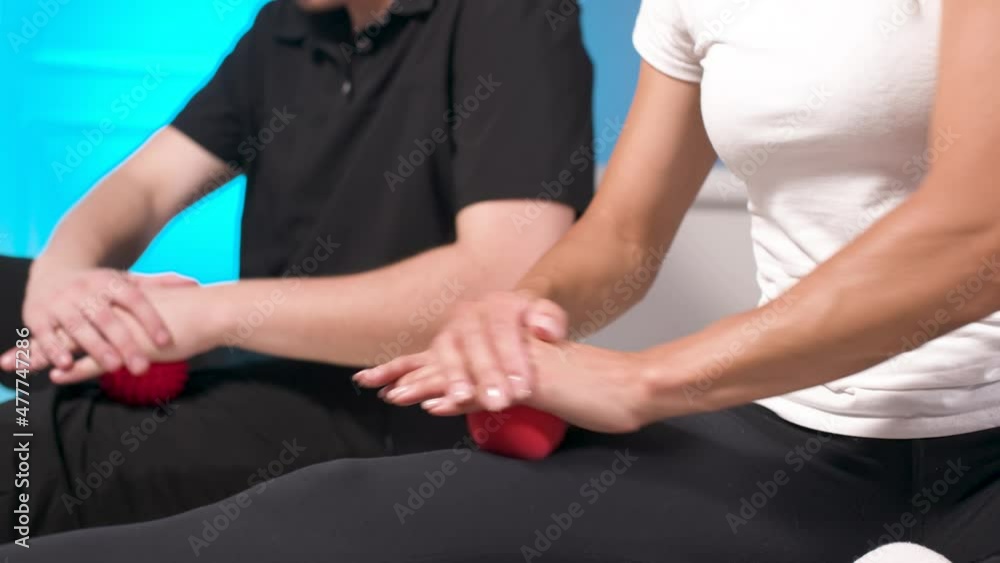 Close-up Myofascial release. A male physiotherapist places a ball for the rehabilitation of the client's leg muscles while sitting technique using a red ball. Self-massage concept. Practical use. Close-up Myofascial release. A male physiotherapist places a ball for the rehabilitation of the client's leg muscles while sitting technique using a red ball. Self-massage concept. Practical use.