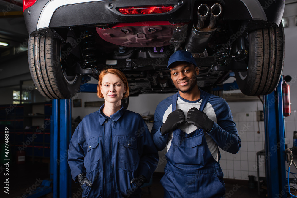 custom made wallpaper toronto digitalMultiethnic mechanics in uniform looking at camera under car in service.