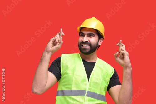 young construction worker feeling haapy and gesturing finger crossed indian pakistani model photo