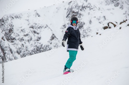 a girl on a snowboard rides down the side of the mountain