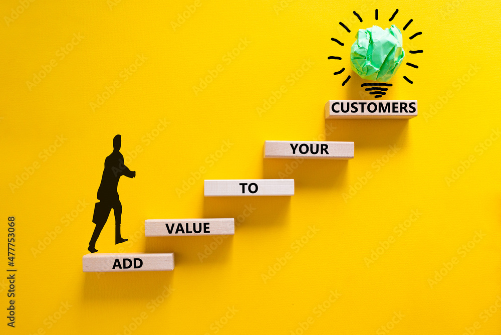 Add value to your customers symbol. Concept words 'Add value to your customers' on wooden blocks on a yellow background, copy space. Businessman icon, light bulb. Business, customers value concept. Add value to your customers symbol. Concept words 'Add value to your customers' on wooden blocks on a yellow background, copy space. Businessman icon, light bulb. Business, customers value concept.
