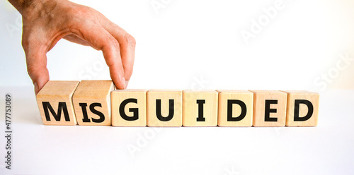 Guided or misguided symbol. Businessman turns wooden cubes and changes the word misguided to guided. Beautiful white table, white background, copy space. Business and guided or misguided concept. photo