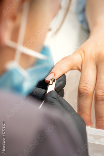 Nail master removing nails cuticle with a nipper  manicure hygiene in a beauty salon