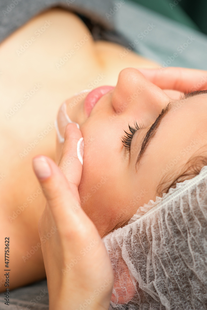 Spa facial skincare. Close-up of a young caucasian woman getting spa moisturizing face massage treatment at beauty spa salon