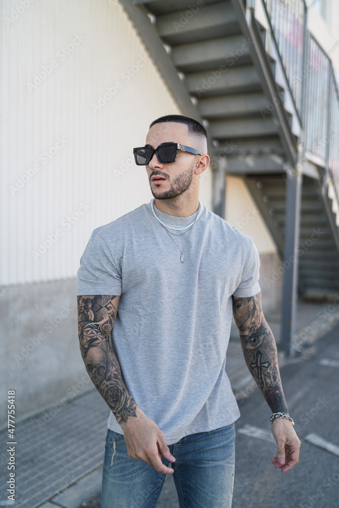 Chico joven tatuado con ropa urbana moderna posando en la calle Chico joven tatuado con ropa urbana moderna posando en la calle